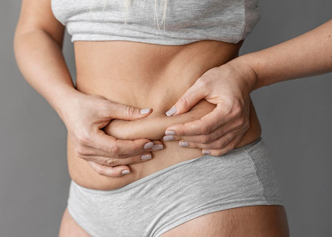 mujer tocándose la piel del abdomen