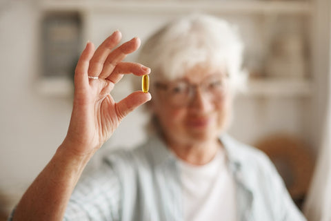 mujer sosteniendo una pastilla de omega 3